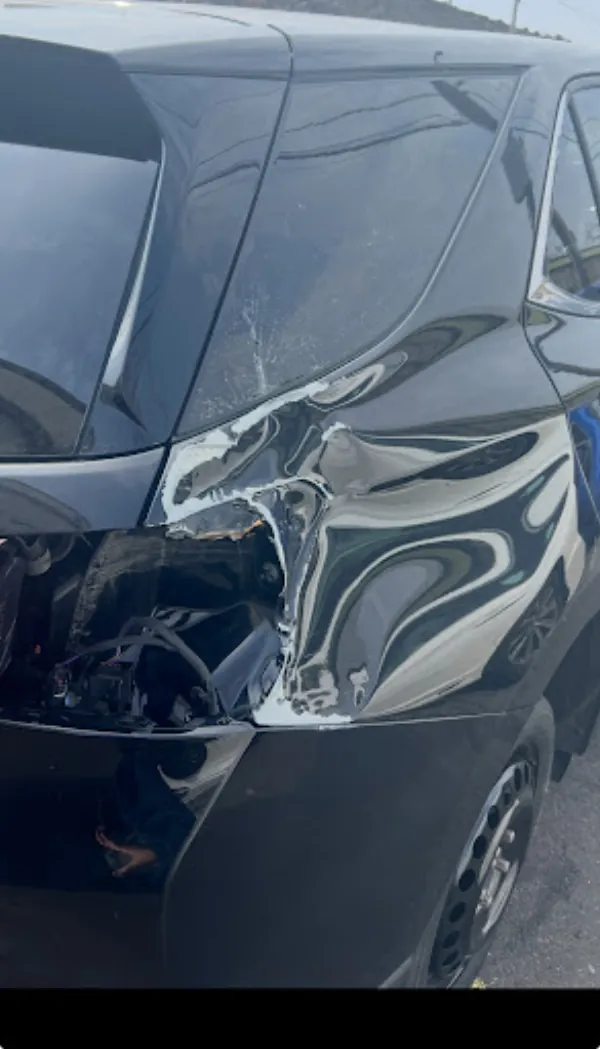 Torn rear quarter panel on a dark hatchback awaiting repair