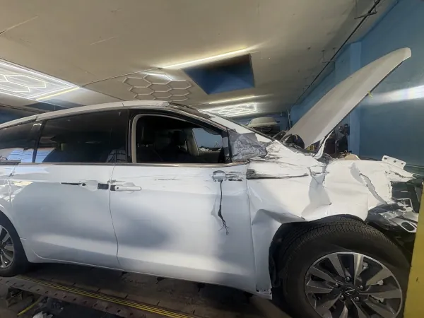 White minivan with heavy front and side collision damage inside the shop