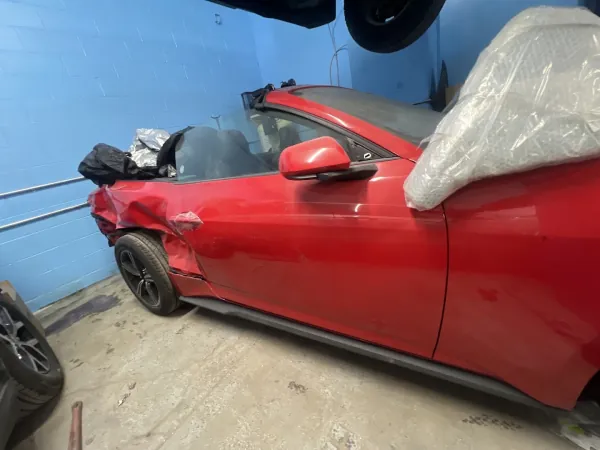 Red convertible with a creased driver-side rear panel